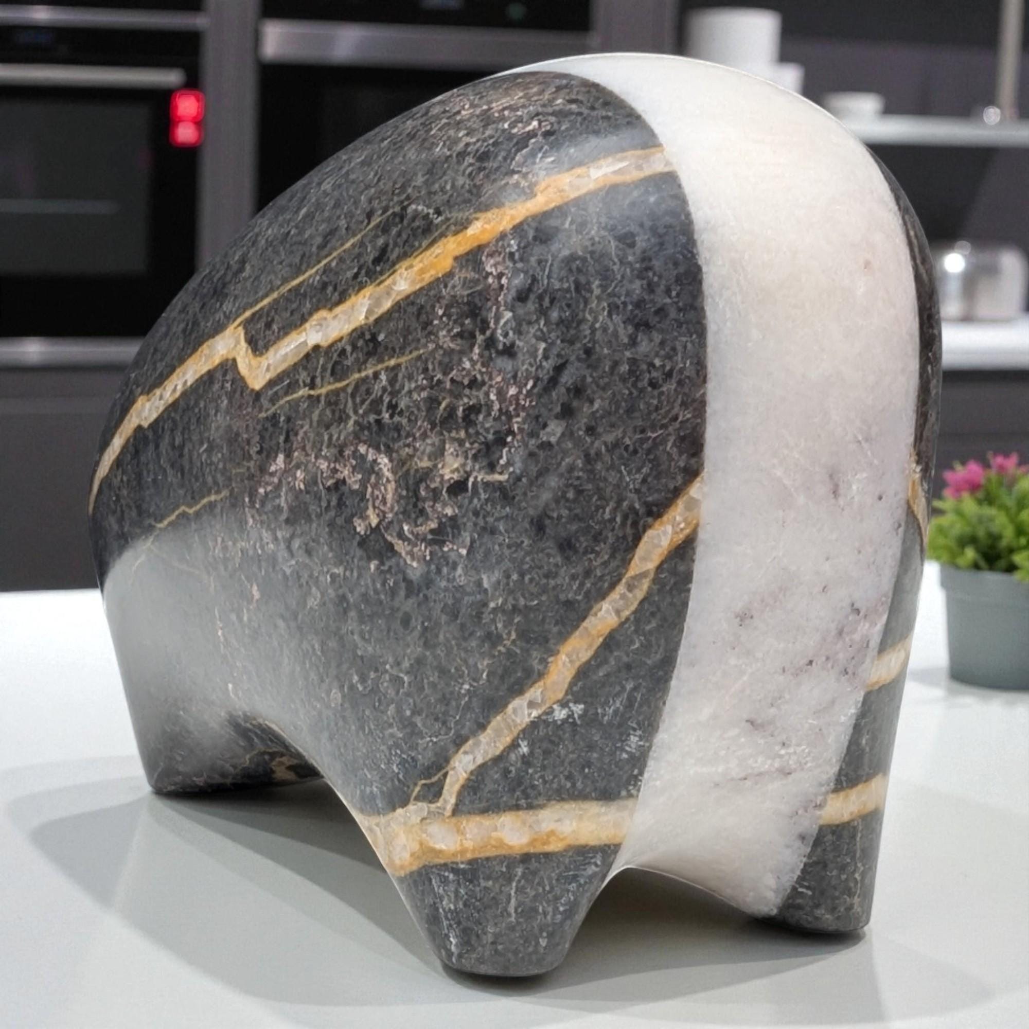 Marble sculpture of a bear on a reflective surface with a blurred indoor background