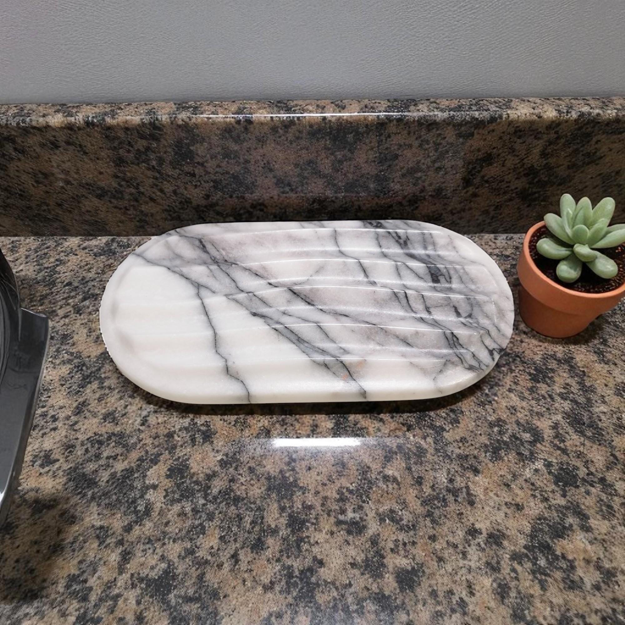 Marble-patterned cutting board on a granite countertop with a small potted plant.