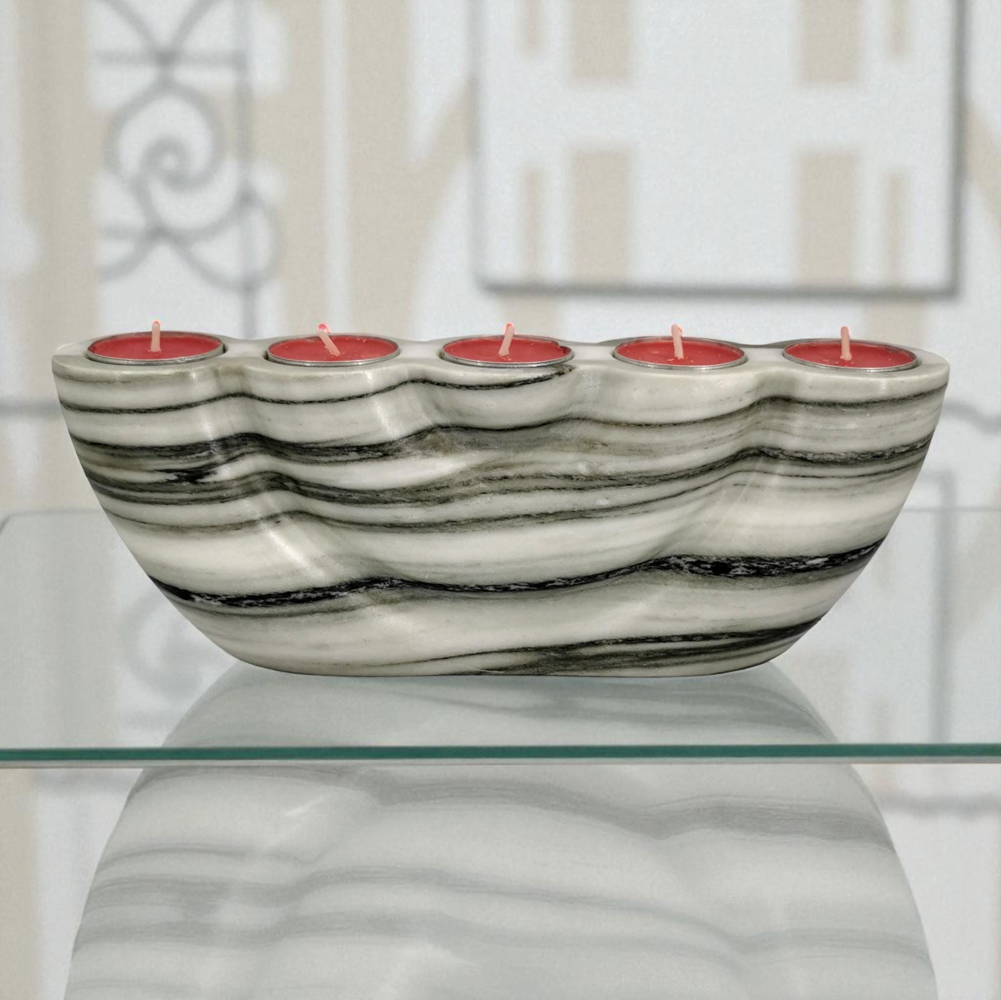 Marble-patterned candle holder with red candles on a glass surface
