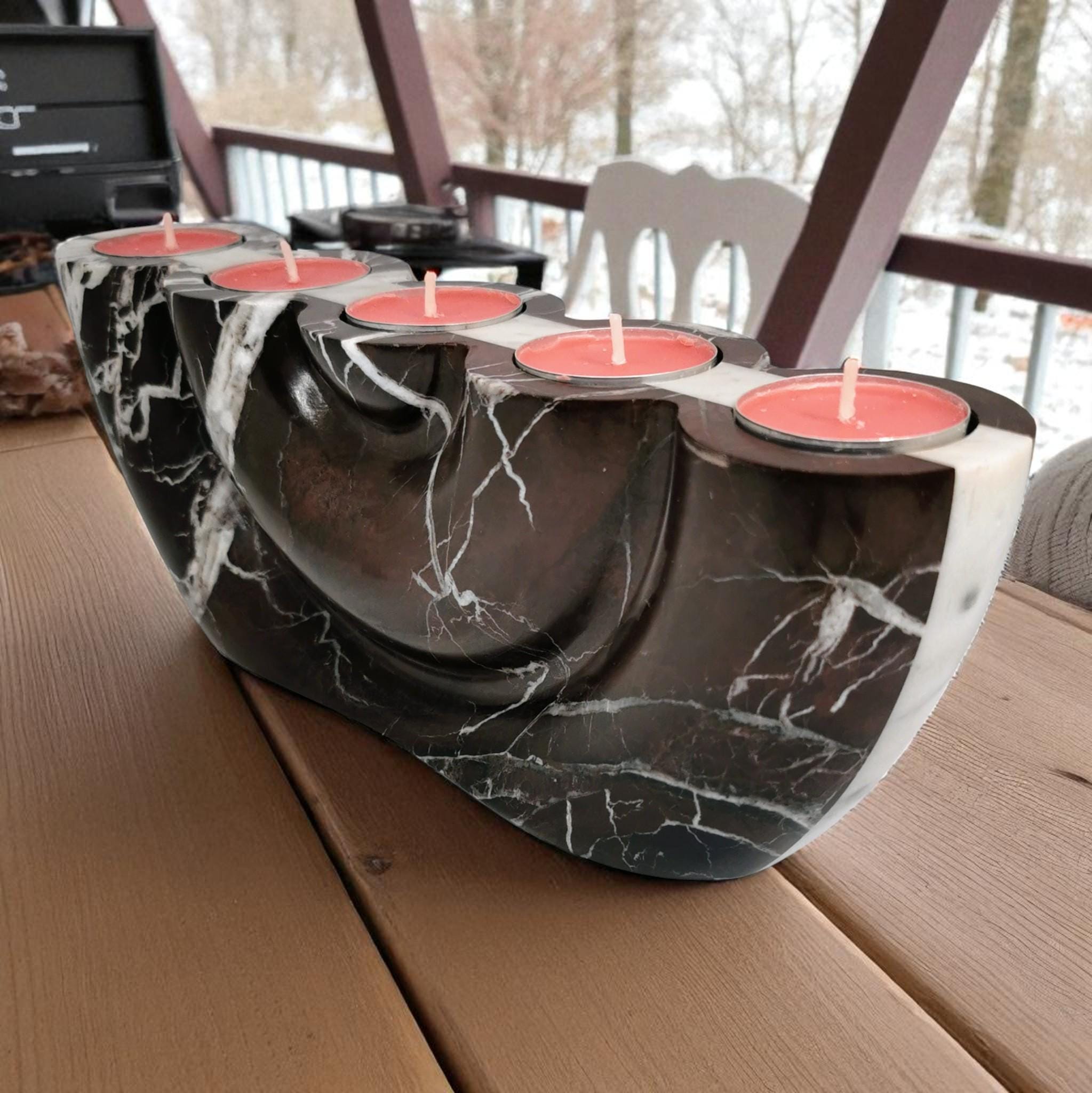 Black marble candle holder with red candles on a wooden surface