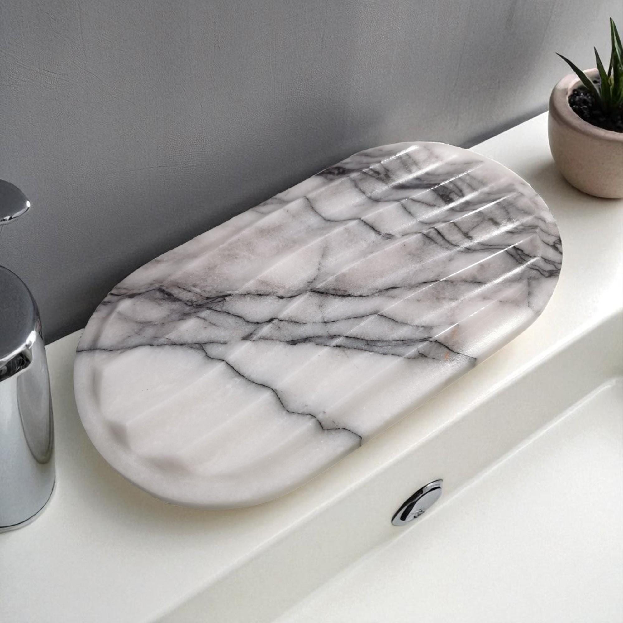 Marble-patterned soap dish on a bathroom counter with a plant in the background