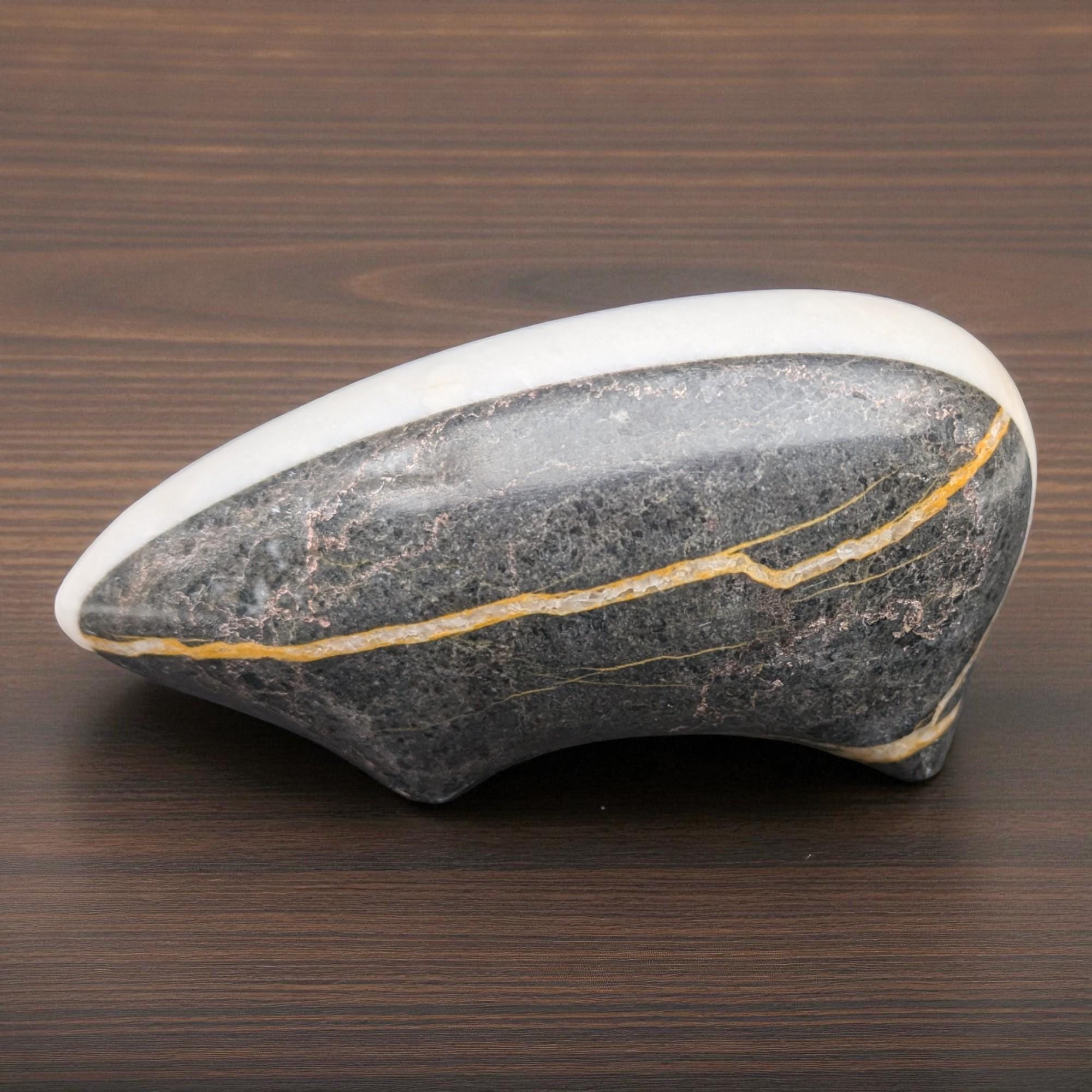 Decorative stone with a white top and gold vein on a wooden surface