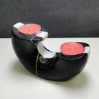 Black and white candle holder with pink candles on a gray background