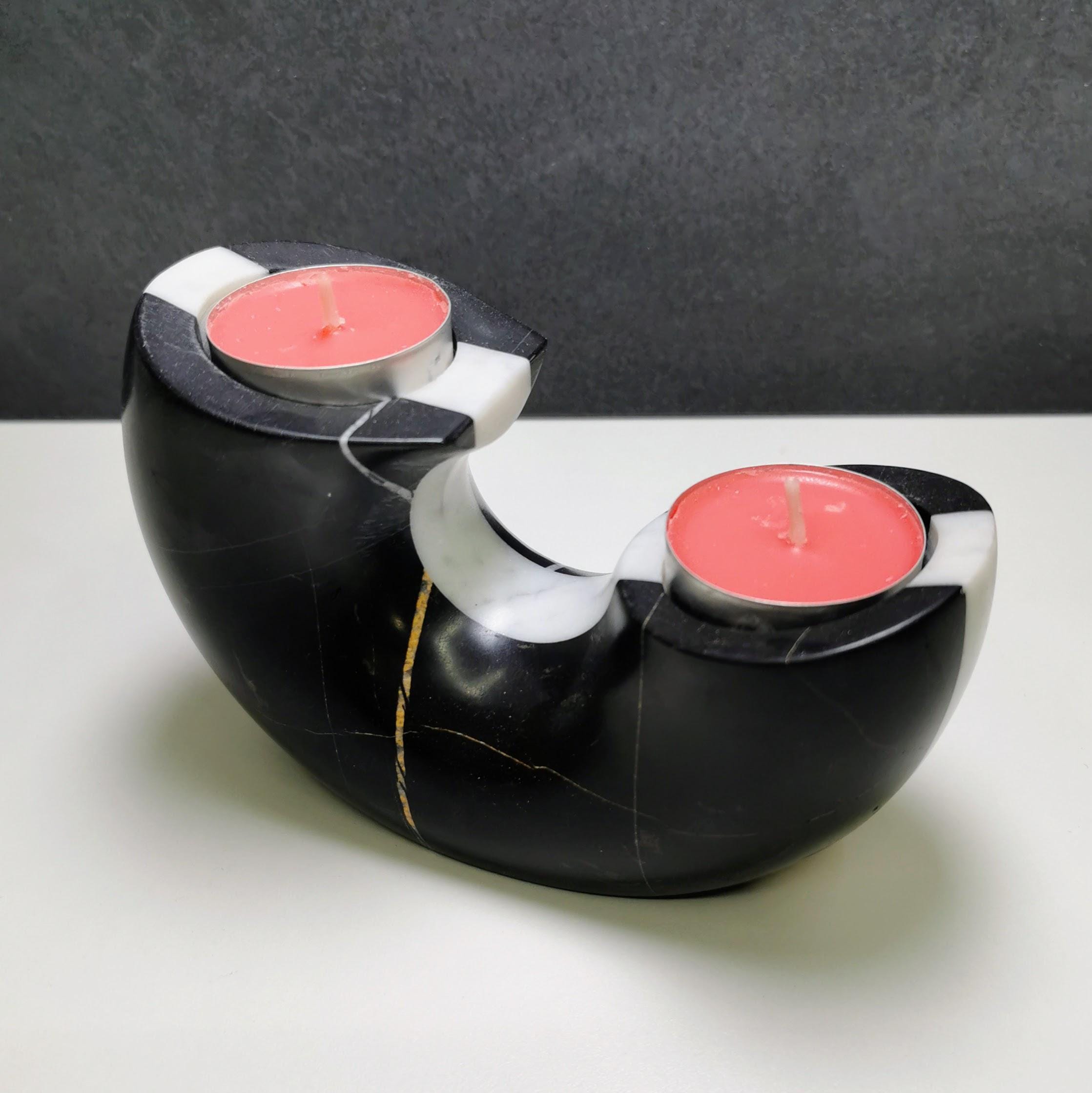 Black and white candle holder with pink candles on a gray background