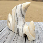 Marble-patterned fish sculpture on a wooden surface with a blurred natural background